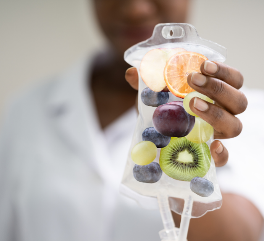 Dark-skinned hand holds colorful fruit IV bag