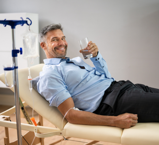 Smiling man enjoys drink while on IV hydration